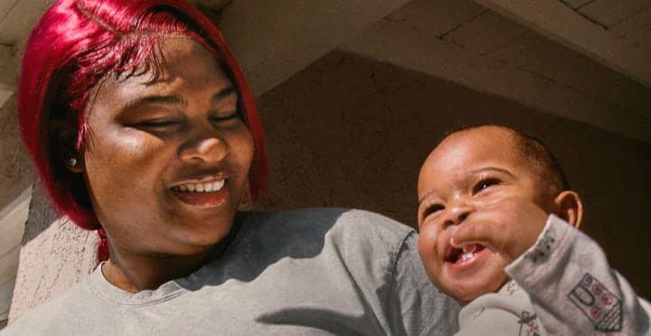 A mother smiling with her laughing baby